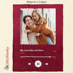 May include: A burgundy blanket featuring a photo of a couple, designed to resemble a music player interface. The text "My Love Mine All Mine" and "Mitksi" are displayed, along with a play/pause button and a progress bar.
