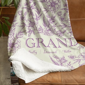 May include: A soft, white fleece throw blanket with a purple floral pattern and the word "GRAND" printed in purple. The names "Sally", "Leonard", "Bella", and "Tony" are printed below the word "GRAND".