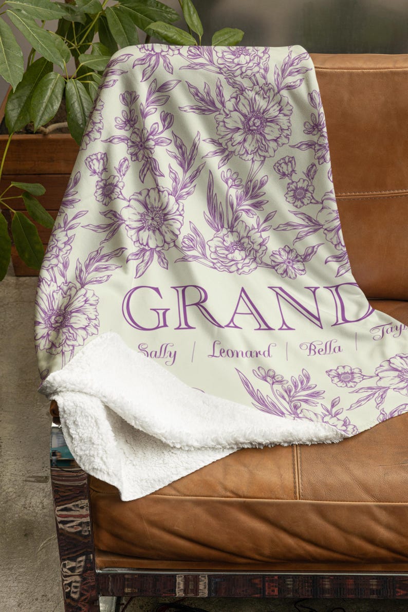 May include: A soft, white fleece throw blanket with a purple floral pattern and the word "GRAND" printed in purple. The names "Sally", "Leonard", "Bella", and "Tony" are printed below the word "GRAND".