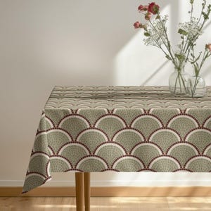 Peut inclure: Une nappe rectangulaire avec un motif répétitif en forme d'éventail dans des tons de vert, blanc et bordeaux. La nappe est posée sur une table en bois. Deux vases en verre avec des fleurs sont sur la table.