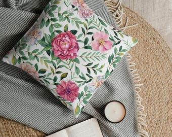 May include: A square throw pillow featuring a white background with a repeating botanical pattern of vibrant pink peonies, soft pink blossoms, and various green leaves and stems arranged in a dense, flowing floral design across the fabric surface.