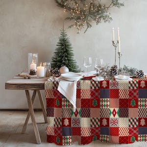 Könnte beinhalten: Eine rechteckige Tischdecke mit einem Patchwork-Design aus roten, grünen und cremefarbenen Quadraten. Das Muster enthält verschiedene weihnachtliche Motive wie Tannenbäume, Schneeflocken, Rauten, Streifen und Punkte für eine festliche Optik.