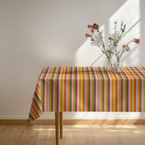 Contemporary rainbow stripe tablecloth styled with neutral plates and glassware. The contrast highlights the colorful pattern beautifully. Suitable for modern and artistic interiors.