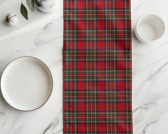 Pode incluir: Um caminho de mesa retangular com um padrão xadrez clássico em vermelho vibrante, verde escuro e azul marinho, com linhas finas brancas e amarelas. O tecido está disposto verticalmente, exibindo uma grade repetitiva de listras coloridas.