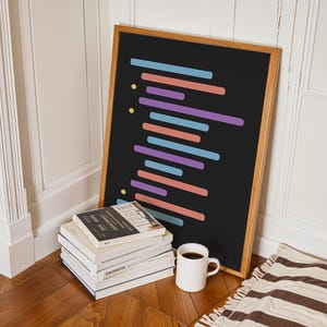 Peut inclure: Une affiche encadr&eacute;e noire avec des lignes horizontales color&eacute;es sur un fond noir. L'affiche est appuy&eacute;e contre une pile de livres et une tasse blanche sur un sol en bois.