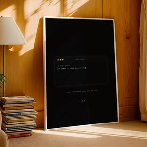 May include: A rectangular framed wall art piece featuring a black background with a centered terminal window graphic. The text inside displays "// FIRST COMMIT" and "git commit -m "Start somewhere."" in green, with "Every masterpiece began with one line." below.