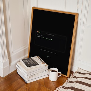 Puede incluir: Un p&oacute;ster negro enmarcado que presenta un gr&aacute;fico de ventana de terminal con el texto "// FIRST COMMIT" y "git commit -m "Start somewhere."" en fuente verde, junto con el texto "Every masterpiece began with one line." y "v1.0".