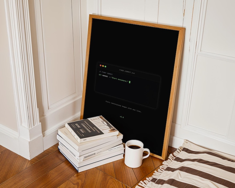 Puede incluir: Un p&oacute;ster negro enmarcado que presenta un gr&aacute;fico de ventana de terminal con el texto "// FIRST COMMIT" y "git commit -m "Start somewhere."" en fuente verde, junto con el texto "Every masterpiece began with one line." y "v1.0".