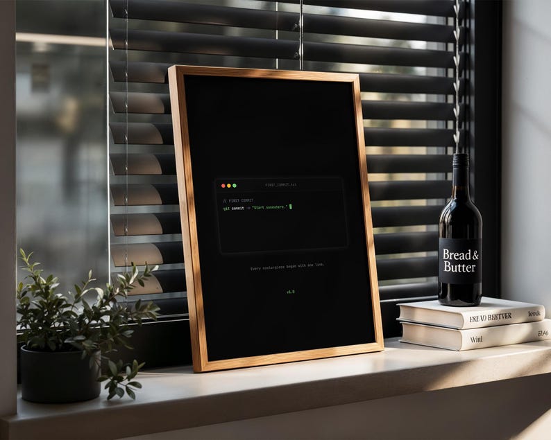 Puede incluir: Un p&oacute;ster vertical enmarcado con fondo negro que presenta un gr&aacute;fico de ventana de terminal con el texto git commit -m "Start somewhere." y la frase Every masterpiece begins with one line. El marco es de madera clara fina.
