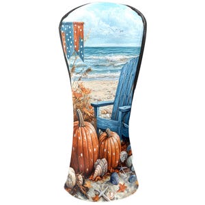 Puede incluir: Funda para la cabeza del palo de golf con una escena de playa con calabazas, conchas marinas y una silla Adirondack azul. La funda tiene un ribete negro y una colorida ilustración de un paisaje costero otoñal.