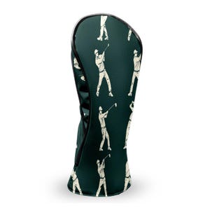 May include: Dark green golf club head cover with a repeating pattern of white golf players in action. The cover has a black trim and a zipper closure. The design is a classic and stylish accessory for any golfer.