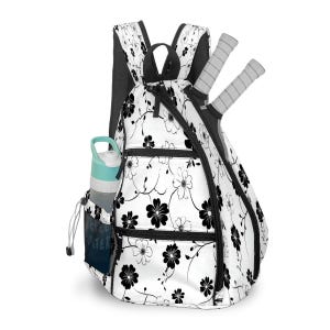 May include: White and black floral print tennis backpack with a water bottle in the side pocket and two tennis rackets. The backpack has multiple zippered compartments and black trim. The water bottle is light blue and white. The text "WATER" is visible on the side pocket.