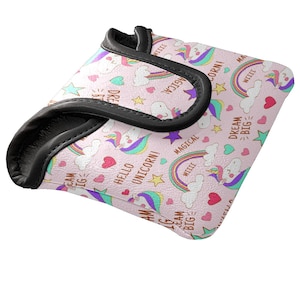 May include: A pink, square-shaped item with a black border, featuring a repeating pattern of unicorns, rainbows, stars, and hearts. Text includes "Hello Unicorn!" and "Dream Big." The item appears to be a golf club head cover.