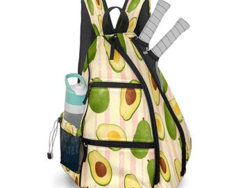May include: A tennis backpack with an avocado pattern on a cream and pink striped background. The bag has a black mesh back, a side pocket with a water bottle, and two tennis rackets. The bag has multiple zippered compartments.