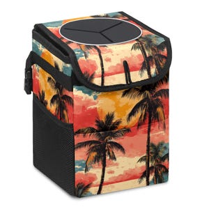 May include: A car trash can with a tropical sunset design featuring palm trees in shades of orange, red, and yellow. The trash can has a black lid with a circular opening and a black mesh side pocket.