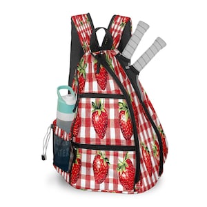 May include: A red and white checkered backpack with a strawberry pattern. The backpack has a black zipper and a side pocket with a water bottle. Two tennis rackets are visible. The side pocket has the word "WATER" printed on it.