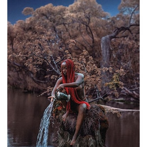 May include: A tarot card titled 17 THE STAR L'&Eacute;TOILE featuring a person with long red hair sitting on a tree stump in a dark pond, pouring water from a metallic pitcher into the water below under a night sky with visible stars and trees.
