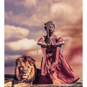 May include: A tarot card featuring a person with dreadlocks wearing a flowing rust-colored dress with arms in a prayer position, standing beside a large male lion. The text 8 THE STRENGTH LA FORCE is printed at the bottom of the card.