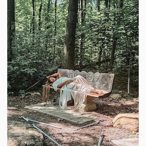 May include: A person with long dreadlocks lies on a carved stone bench, wearing a light blue and white draped garment. Three silver swords are positioned on the ground in front of the bench. The text 4 OF SWORDS D'&Eacute;P&Eacute;E is at the bottom.