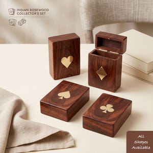 May include: Four rectangular Indian rosewood boxes for playing cards, each featuring a brass inlay of a card suit: heart, diamond, spade, and club. One box is shown open with a hinged lid. Text reads: INDIAN ROSEWOOD COLLECTOR'S SET.