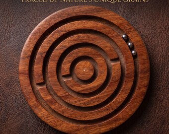 Puede incluir: Un rompecabezas de laberinto circular de madera de palisandro indio marrón con vetas visibles. El rompecabezas presenta pistas circulares concéntricas y tres pequeñas bolas de metal plateado. El texto en la parte superior dice: EXQUISITE INDIAN ROSEWOOD PATHS TRACED BY NATURE'S UNIQUE GRAINS.