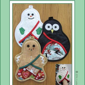Puede incluir: Tres agarraderas para ollas con temática navideña: un muñeco de nieve, un pingüino y un hombre de jengibre. Cada agarradera tiene un borde rojo y verde y un diseño festivo. Las agarraderas están hechas de tela y están diseñadas para proteger las manos de las superficies calientes.