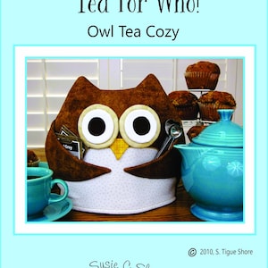 May include: A brown owl-shaped tea cozy with white eyes and a yellow beak. The cozy is sitting on a wooden table next to a blue teapot and a plate of muffins. The text "Tea For Who! Owl Tea Cozy" is at the top of the image.