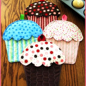 May include: Four colourful cupcake-shaped pot holders with different patterns. The pot holders are made of fabric and have a quilted design. They are perfect for protecting your hands from hot dishes.