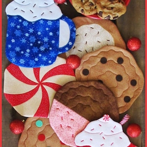 Op de afbeelding: Set van acht gestikte onderzetters met een kerstthema. De onderzetters zijn gevormd als koekjes en mokken met warme chocolademelk met slagroom en sprinkles. De onderzetters zijn versierd met rode, witte en blauwe stof en hebben verschillende patronen, waaronder sneeuwvlokken, pepermuntstokken en chocolade chips.