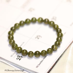 May include: A green gemstone bracelet with round beads. The bracelet is made of natural stones and is approximately 7 inches in length.