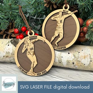 May include: Two wooden Christmas ornaments with athletes in action. One ornament features a female athlete with the name "Madison" and the text "Cochrane High 2025". The other ornament features a male athlete named "Nolan" and the text "25 Champion".