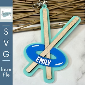 May include: A turquoise blue and white key chain with a blue and white inner tube and two wooden paddles. The inner tube has the name "EMILY" written on it.