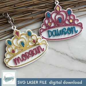 May include: Two gold glitter princess crown-shaped keychains with the names "Dawson" and "Morgan" written in pink glitter.