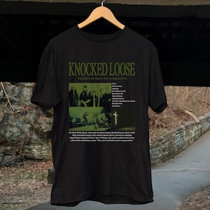 May include: Black t-shirt with a graphic print of the album cover for "Knocked Loose - You Won't Go Before You're Supposed To". The album cover features a band with a green and black color scheme.