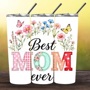 May include: White tumbler with a floral design and the words "Best MOM ever." The letters are decorated with patterns and colors. Pink and yellow butterflies and flowers surround the text. Includes a silver straw.