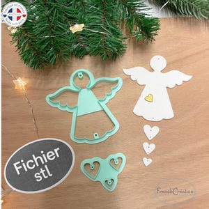 May include: An assortment of angel-shaped craft supplies, including a light green angel-shaped cookie cutter, a white angel cutout with a gold heart, and white heart cutouts. The image also includes a sign that says "Fichier stl".