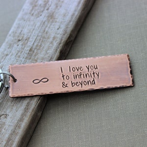 May include: Copper keychain with an infinity symbol and the text "I love you to infinity & beyond".
