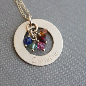 May include: Gold necklace with a round pendant that says "Grandma" and has a cluster of colorful crystals hanging from it.