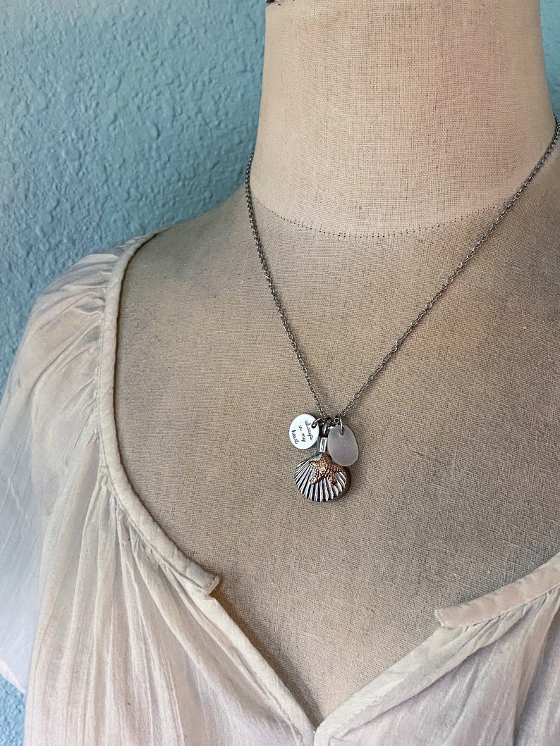 May include: A silver chain necklace with a seashell charm, a small round charm with the text "Always in my heart", and a clear glass charm.
