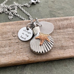 May include: Silver chain necklace with a seashell charm, a small starfish charm, and a round charm with the inscription "always in my heart".