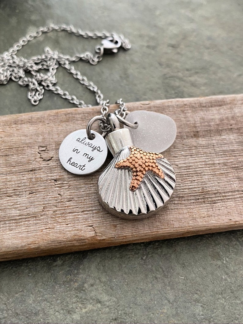 May include: Silver chain necklace with a seashell charm, a small starfish charm, and a round charm with the inscription "always in my heart".