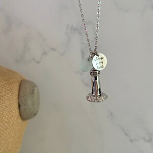 May include: Silver necklace with a lighthouse charm and a small round charm that says "always in my heart".
