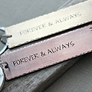 May include: Two metal keychains with the words "Forever & Always" engraved on them. One keychain is gold and the other is copper. The copper keychain has the date "04.04.14" engraved on it.