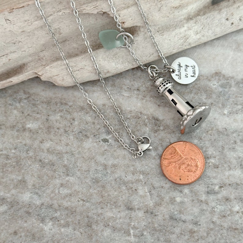 May include: Silver chain necklace with a lighthouse charm and a small round charm that says "always in my heart".