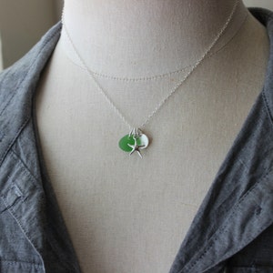 May include: A silver chain necklace with a green and white sea glass charm and a silver starfish charm.
