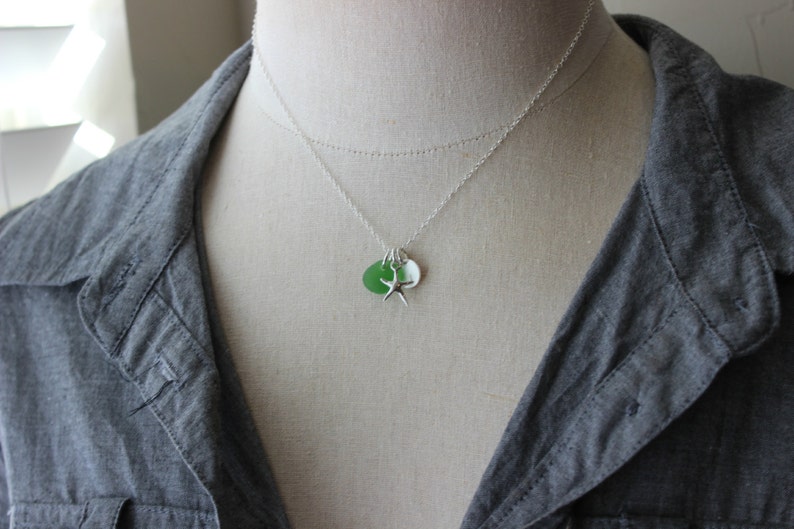 May include: A silver chain necklace with a green and white sea glass charm and a silver starfish charm.