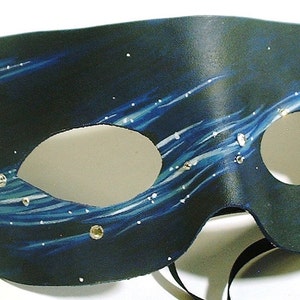 May include: A black leather masquerade mask with a blue and white starry night design. The mask has two eye holes and a black ribbon tie.
