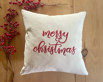 May include: White throw pillow with red embroidered text that reads "merry christmas".