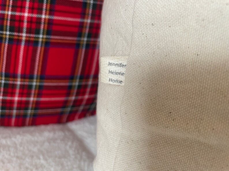 May include: A white canvas pillow with a label that reads "Jennifer Helene Home".