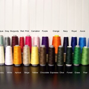 K&ouml;nnte beinhalten: Eine Sammlung von 24 Garnrollen in verschiedenen Farben, darunter Teal, Aqua, Grau, Burgunder, Rot, Pink, Nelke, Lila, Orange, Marine, Royal, Azur, Himmelblau, Schwarz, Elfenbein, Wei&szlig;, Aprikose, Beige, Gelb, Schokolade, Espresso, Oliv, Wald, Gras, Birne und Lavendel.